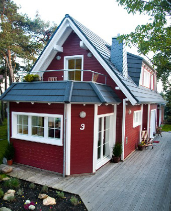 Rotes Holz-Musterhaus mit großem Dach und Terrasse